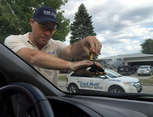 windshield repair technician repairing chip on windshield.